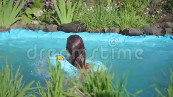 女孩在一个小池塘里游泳这个孩子在炎热的夏日里享受清凉的水快乐的童年花草生长视频的预览图