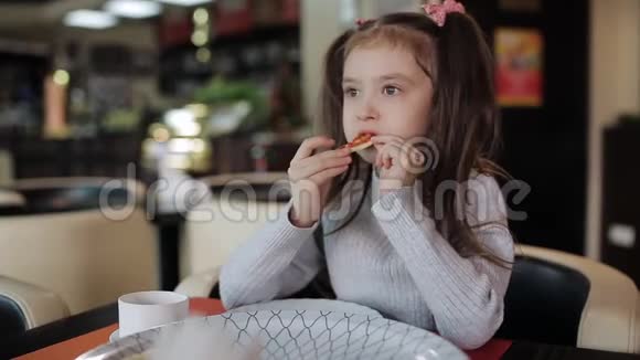 一个小女孩在吃着一块带有拉伸奶酪的披萨婴儿正在吃不健康的食物视频的预览图