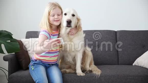儿童生活中的装置一个小女孩和她的狗在智能手机上自拍位置客厅的沙发视频的预览图