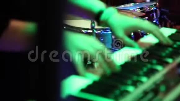 女手在彩色舞台灯光下弹奏电钢琴特写视频的预览图