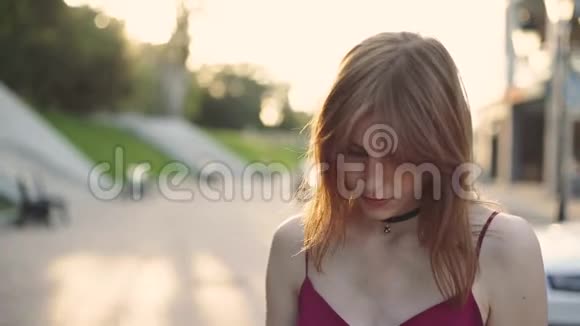 美丽的年轻红发女摩托车手戴上她的黑色头盔日落或日出的街道视频的预览图