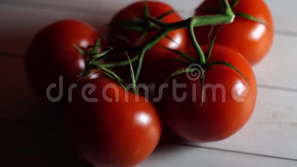白色木制背景上的红色西红柿从上面看到的在树枝上洗过的蔬菜生食的概念视频的预览图