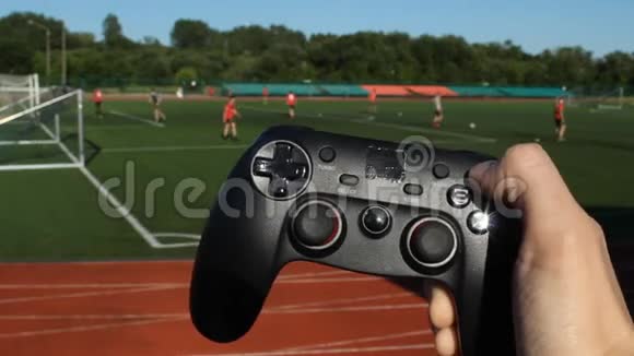 男人手拿着一个游戏操纵杆在他们踢足球的体育场的背景上按下按钮视频的预览图