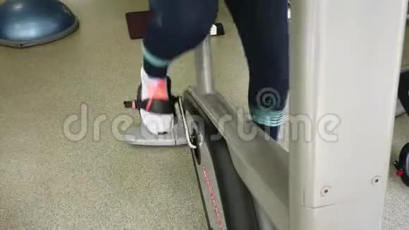 年轻女孩在运动健身房骑着运动自行车跑步视频的预览图