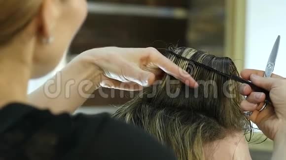 芭比娃娃的手用剪刀在美容院塑造男人的头发慢动作视频的预览图