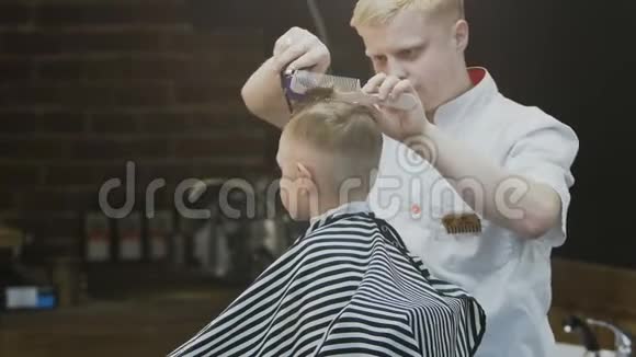 理发店时髦的小男孩在理发店理发一个漂亮的男孩和一个时尚的理发师理发视频的预览图
