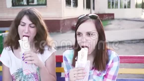 女孩们坐在长凳上吃沙瓦玛户外快餐的特写视频的预览图