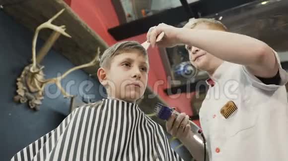 理发师给理发店的一个小男孩做了一个时尚的发型理发师用理发器理发视频的预览图