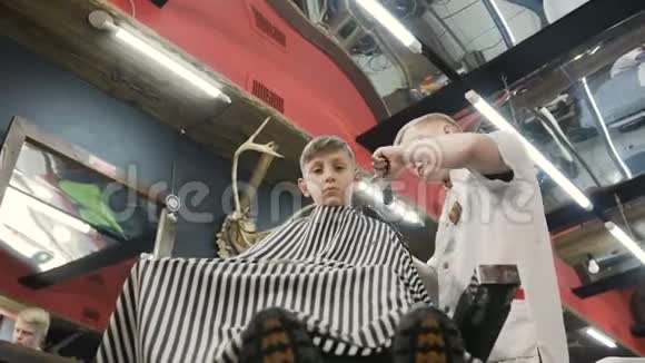 从底部看理发店有客户小孩的理发师男理发店里用修剪机理发可爱的孩子视频的预览图
