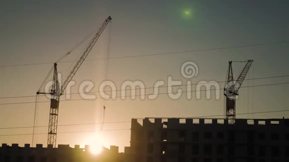 日落时吊车及建筑施工现场剪影工人在天空的背景上视频的预览图