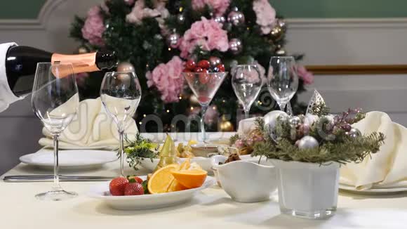 餐厅概念新年和圣诞大餐桌戴手套的侍者从瓶子里倒出香槟切片视频的预览图