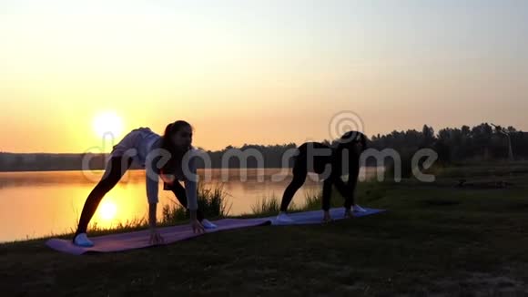 太阳落山时带着教练在湖上练习瑜伽的怀孕女孩视频的预览图
