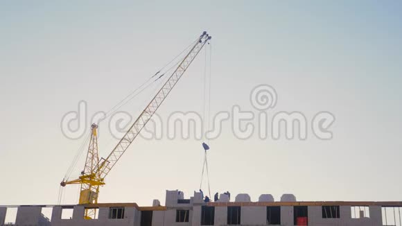日落时吊车及建筑施工现场剪影工人在天空的背景上视频的预览图