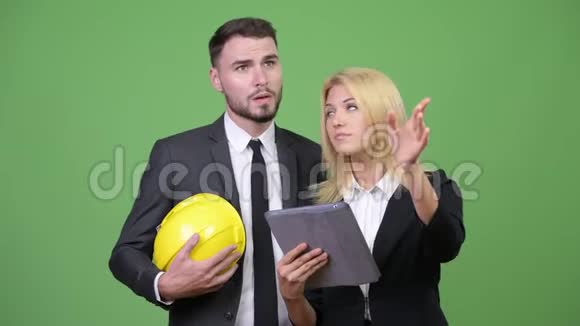 年轻的商务夫妇在开会时一起使用数码平板电脑视频的预览图