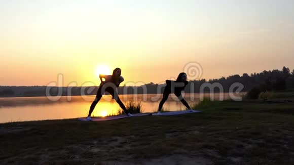 超级日落和妇女向前弯曲和培训在湖岸视频的预览图