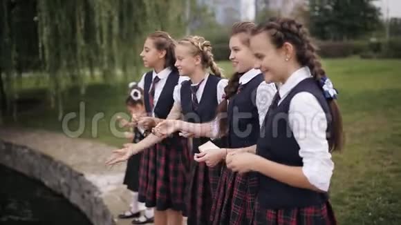 穿校服的学生在学校院子里的池塘里喂鸭子女子学院的女学生穿着同一所学校视频的预览图