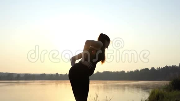 孕妇站在垫子上向前走在日落的岸上慢悠悠地走视频的预览图