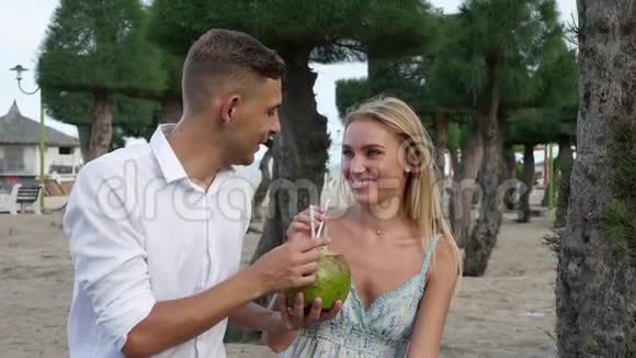 年轻的幸福夫妇坐在公园里谈笑风生喝着椰子浪漫的概念高清1920x1080视频的预览图