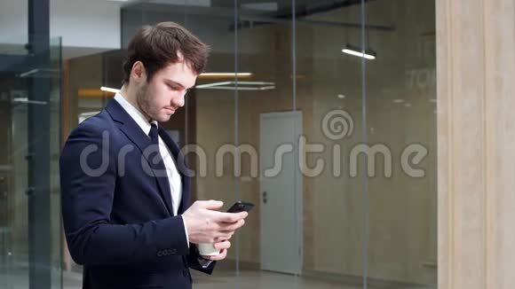 咖啡休息开始自信的人拿着咖啡杯在大厅里散步时用他的智能手机视频的预览图