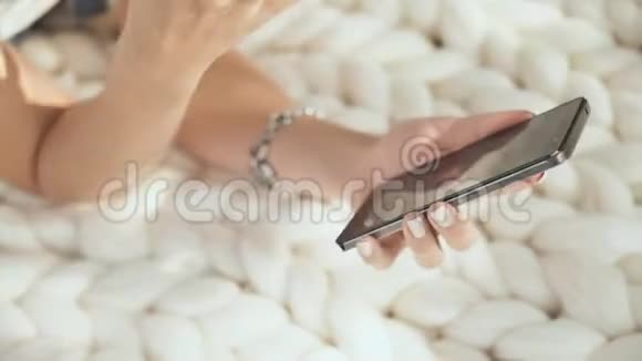 一个年轻的女孩躺在公园里的白色格子布上在电话里拨了一条信息双手特写视频的预览图