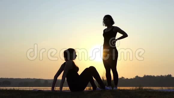 日落时分孕妇与教练一起练习瑜伽视频的预览图