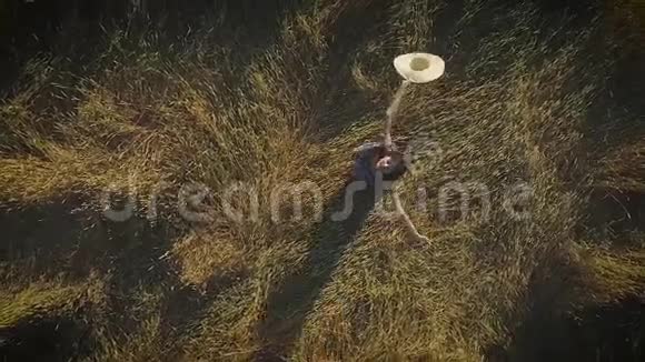 空中飞行迷人的女孩正在草地上旋转拿着一顶草帽从上面看慢动作视频的预览图