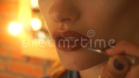 化妆师为一个年轻女孩涂了一层鲜艳的口红视频的预览图