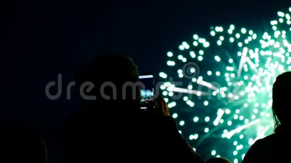 人们在手机上燃放烟花通过智能手机屏幕观看敬礼视频的预览图
