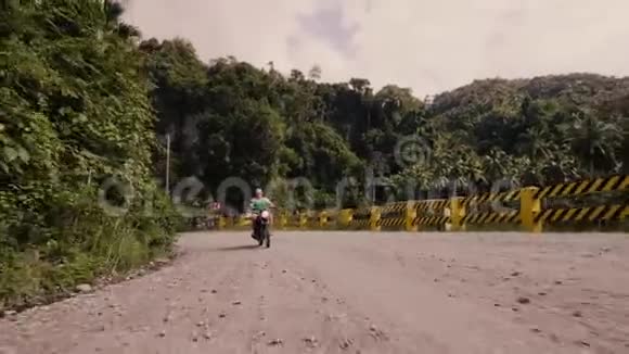 成年男子骑摩托车上路热带森林景观夏天骑摩托的老人视频的预览图