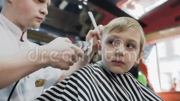 理发师为理发店的一个小男孩做了一个时尚的理发这个神奇的小男孩换了一个新发型视频的预览图