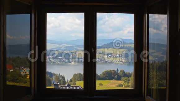 年轻的女士打开窗户看着山湖村和天空视频的预览图