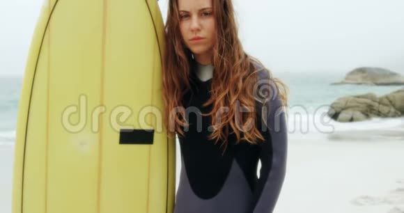 高加索女性冲浪者站在海滩上冲浪板的正面景色视频的预览图