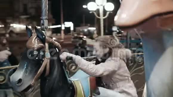 一个小女孩在游乐园里爬玩具马快乐的女孩骑着旋转木马坐在马上视频的预览图