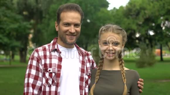 开朗的父亲和十几岁的女儿微笑着走进镜头竖起大拇指视频的预览图