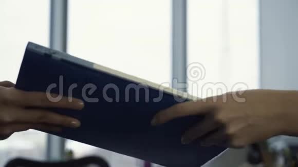 特写工人拿着一个蓝色的文件夹和秘书上交的文件纸工的概念视频的预览图