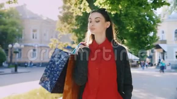 一个有魅力的女人带着购物袋在城里走来走去视频的预览图