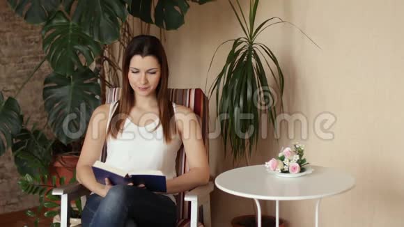 那个年轻漂亮的女孩坐在椅子上看书那个女人在书里找东西视频的预览图