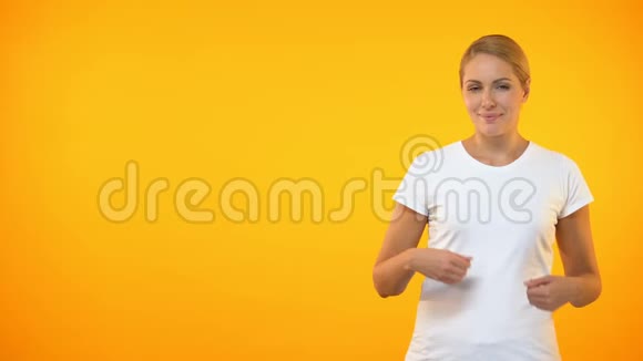 年轻的微笑女人在橙色背景下展示模板公告视频的预览图