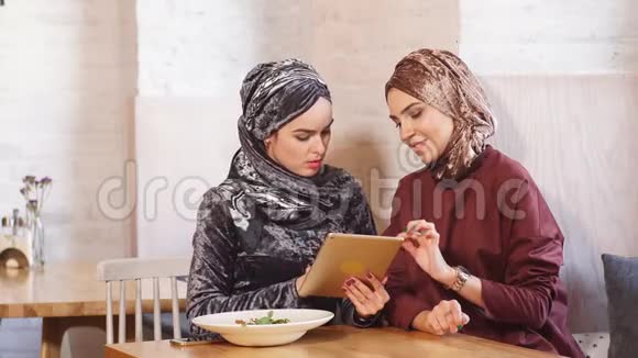 女穆斯林大学生在咖啡馆里使用平板电脑视频的预览图