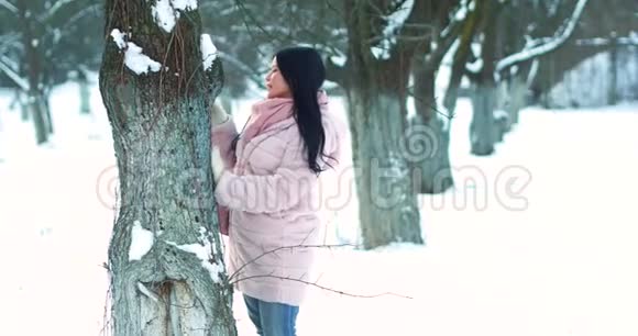 美丽的女人在雪地花园里照顾树视频的预览图