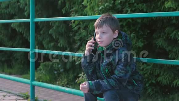 男孩打电话坐在公园里说话视频的预览图