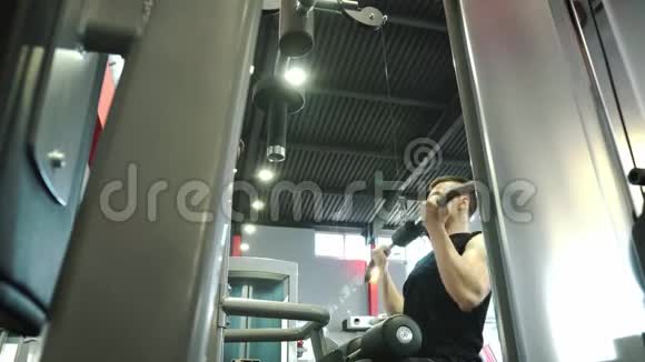 年轻有目的的人在健身房的模拟器上从事视频的预览图