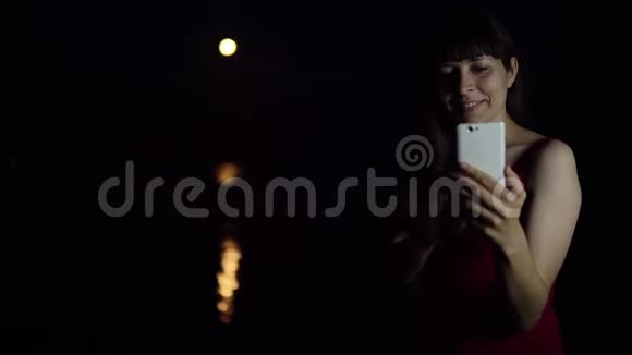 一个年轻的女人用智能手机相机对着红月自拍视频的预览图