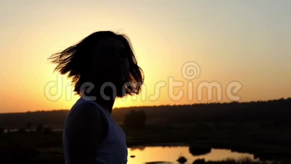 年轻美丽的女人把头发整理好看着斯隆莫的日落视频的预览图