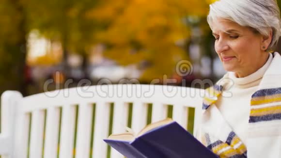 快乐的老年女性在秋公园读书视频的预览图