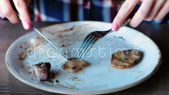 特写女人她的手切一块猪肉在煤上用土豆肉汁和盘子上的绿色煮熟视频的预览图
