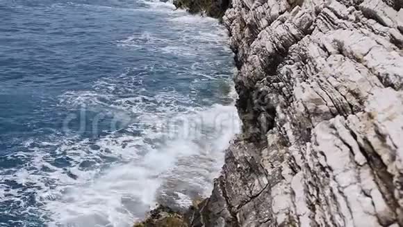 美丽的波浪飞溅在Petrovac的层状岩石悬崖上黑山亚得里亚海海浪拍打着岩石视频的预览图
