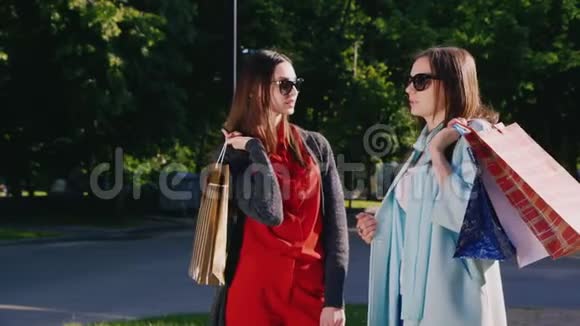 两个女朋友带着购物袋在户外聊天视频的预览图