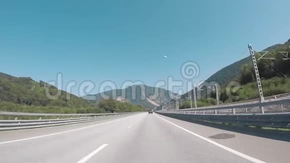 从铁路附近的高速公路上的汽车上观看并通过火车对抗蓝天和山脉场景索契视频的预览图