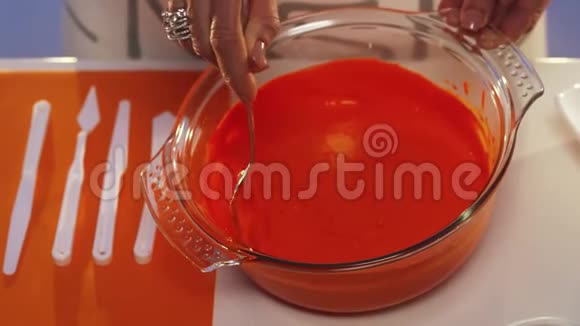 女人白色桌子上的大玻璃碗里有戒指的手搅动着橙色的物质视频的预览图